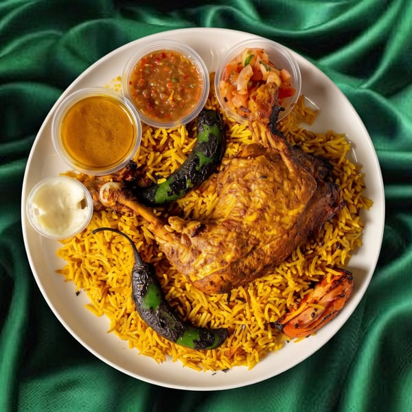 Chicken mandi with yellow rice, grilled peppers, and three dipping sauces on a green silk background.